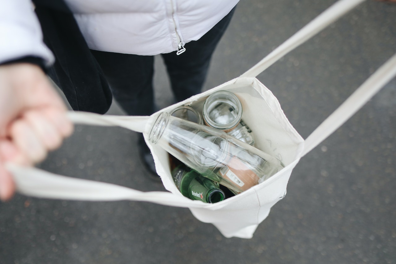 Pessoas, mostrando uma sacola aberta com vidros para reciclagem